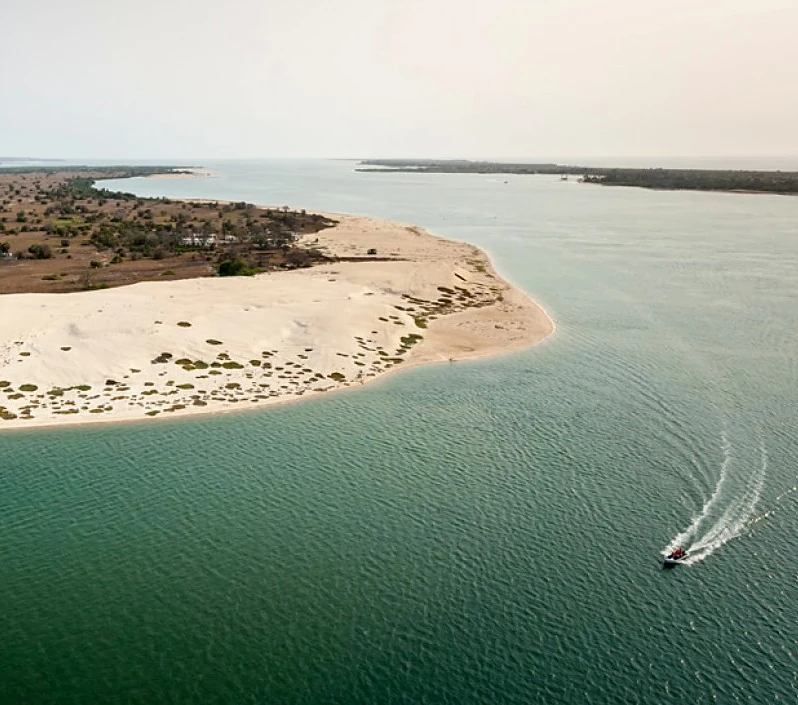 Ponta da Ilha do Mussulo com um barco a cortar a água turquesa