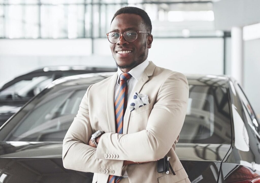 young-black-businessman-on-auto-salon-background-car-sale-and-rent-concept-1